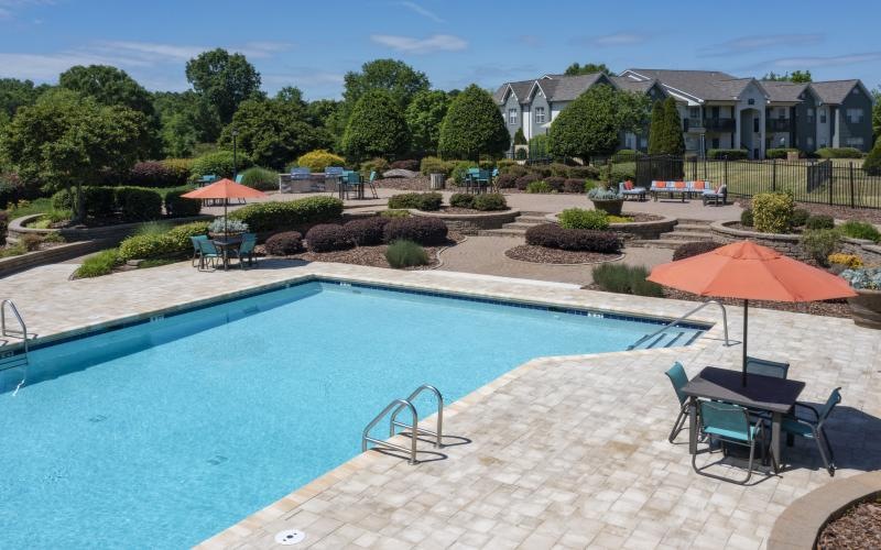 a pool with a patio and umbrellas by it